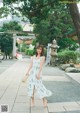 A woman in a white dress is walking down a sidewalk.