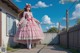 A woman in a pink dress is walking down a sidewalk.