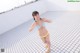 A woman in a bikini standing on a tiled floor.