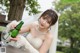 A woman in a wedding dress holding a bottle of wine.