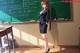 A woman standing in front of a blackboard in a classroom.