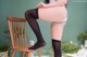 A woman sitting on a chair wearing black stockings.