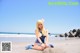 A woman in a sailor outfit sitting on the beach.