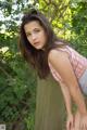 A young woman leaning against a tree in the woods.