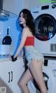 A woman standing in front of a washing machine in a kitchen.